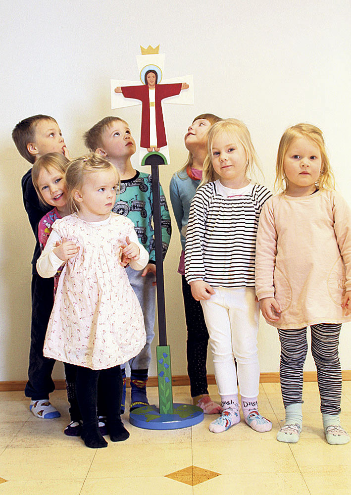 Sju barn i lägre skolåldern runt ett kors.