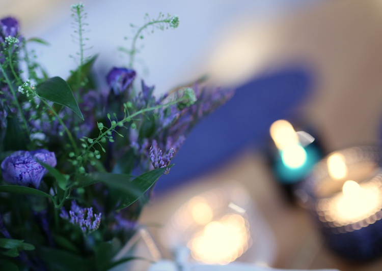 Blå blommor och tända ljus på ett bord.