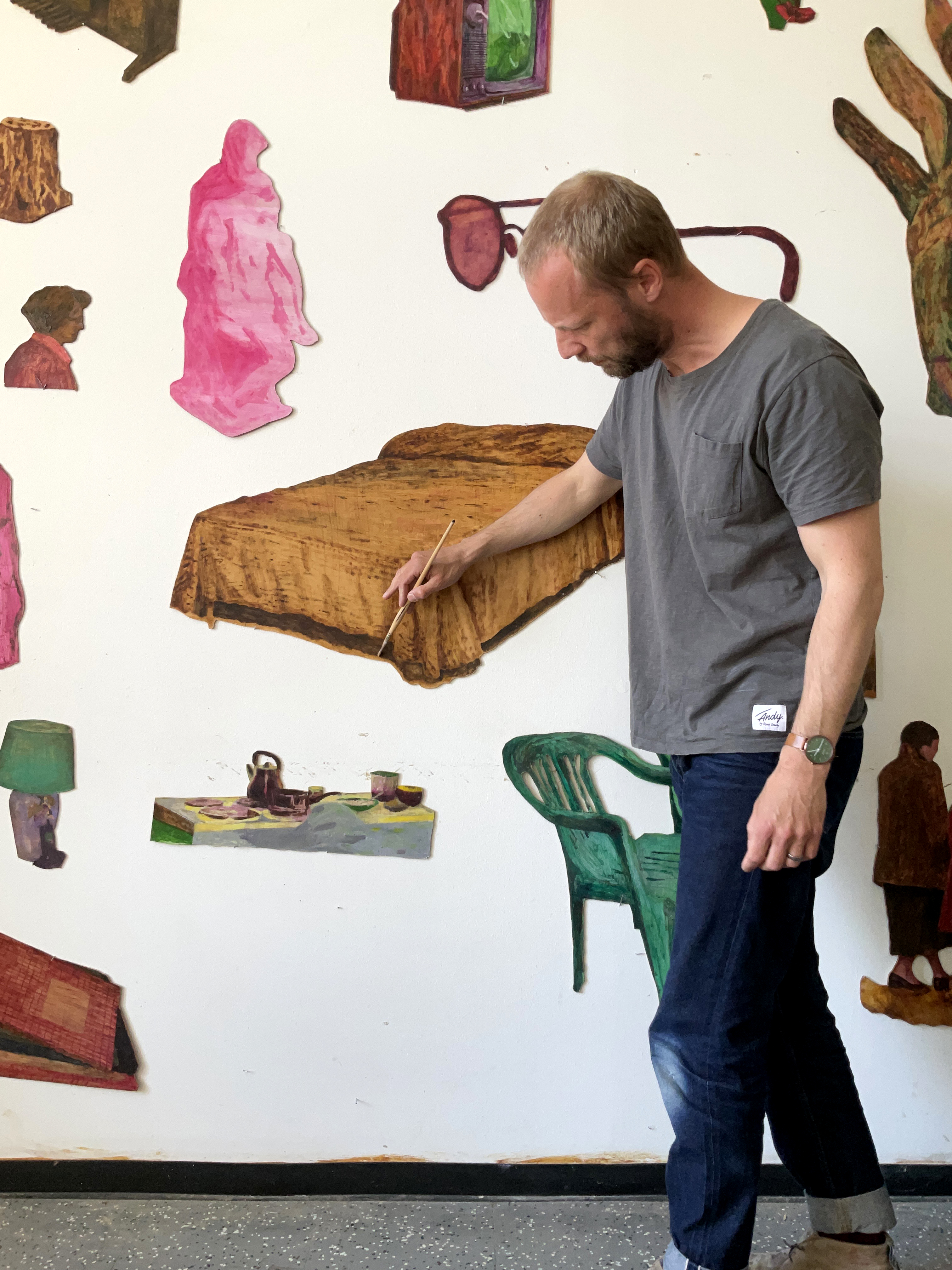 Mattias Löfqvist står framför sin konst, som hänger på en vit vägg.