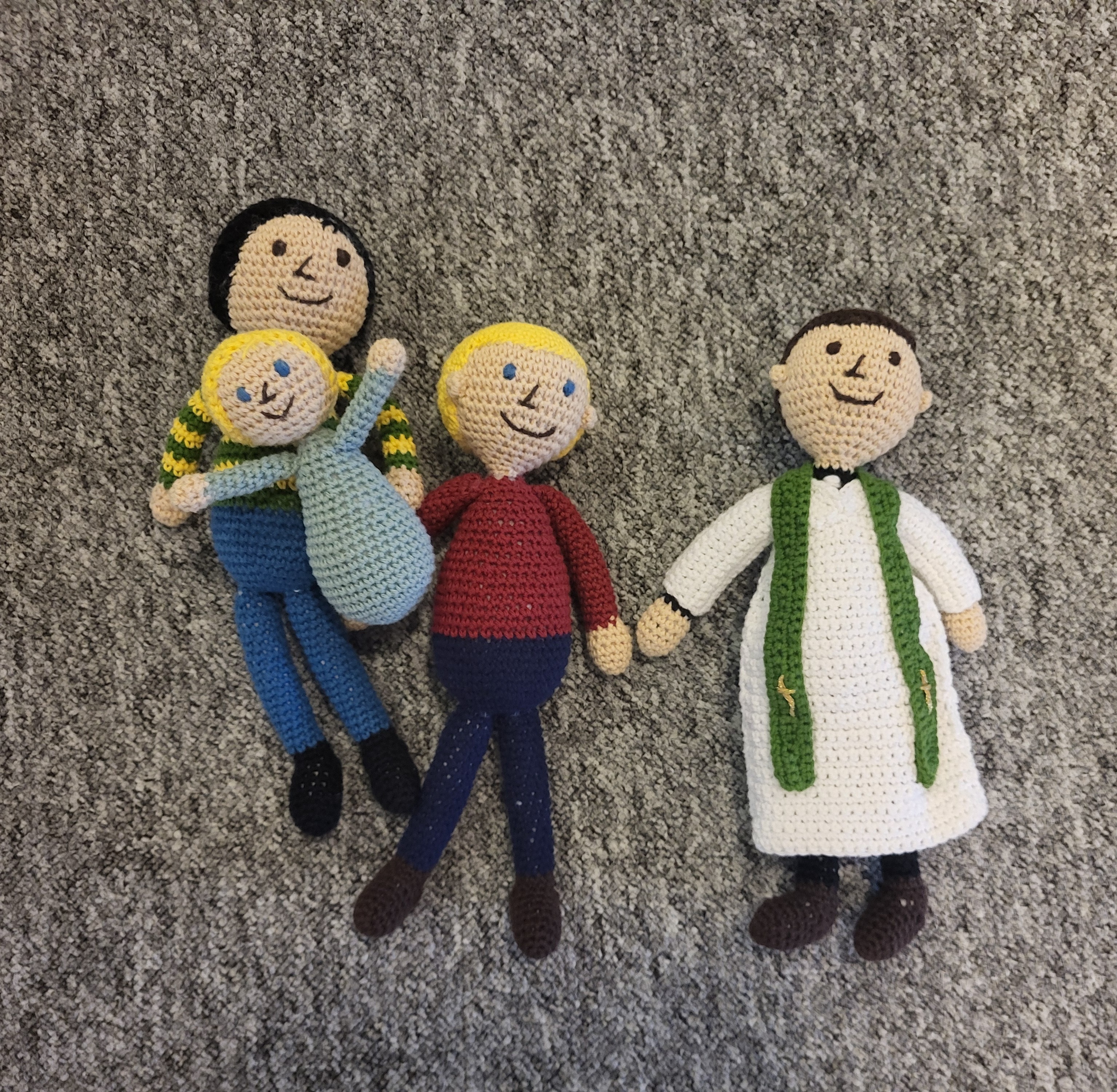 Illustrationsbild. Virkade dockor som föreställer en barnfamilj och en präst.