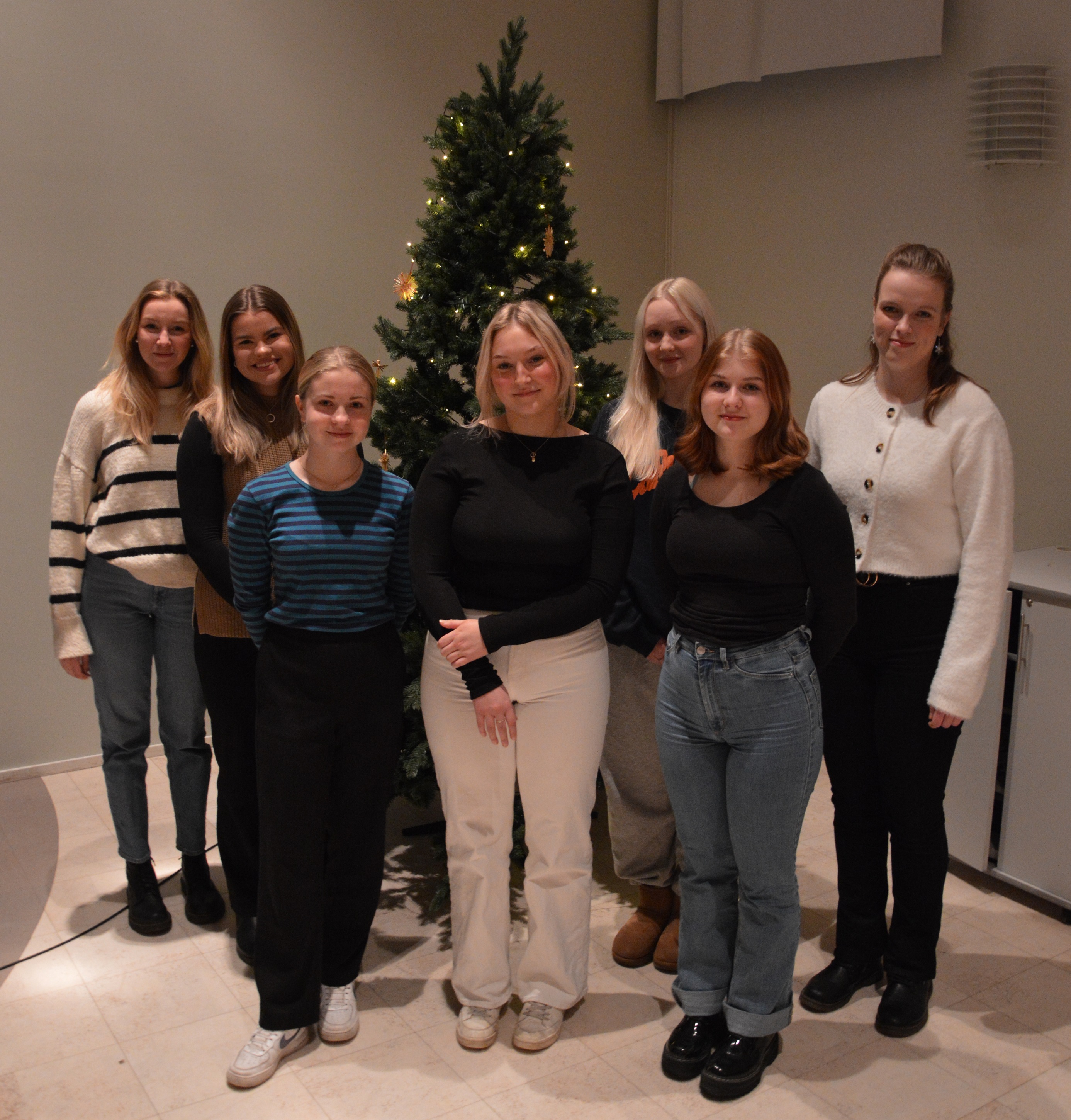 Marie Brunell, Emma Vikman, Alma Långbacka, Agnes Wikar, Kia Kulla, Ida-Maria Åkerlund och Krista Kuniala uppställda framför julgranen.