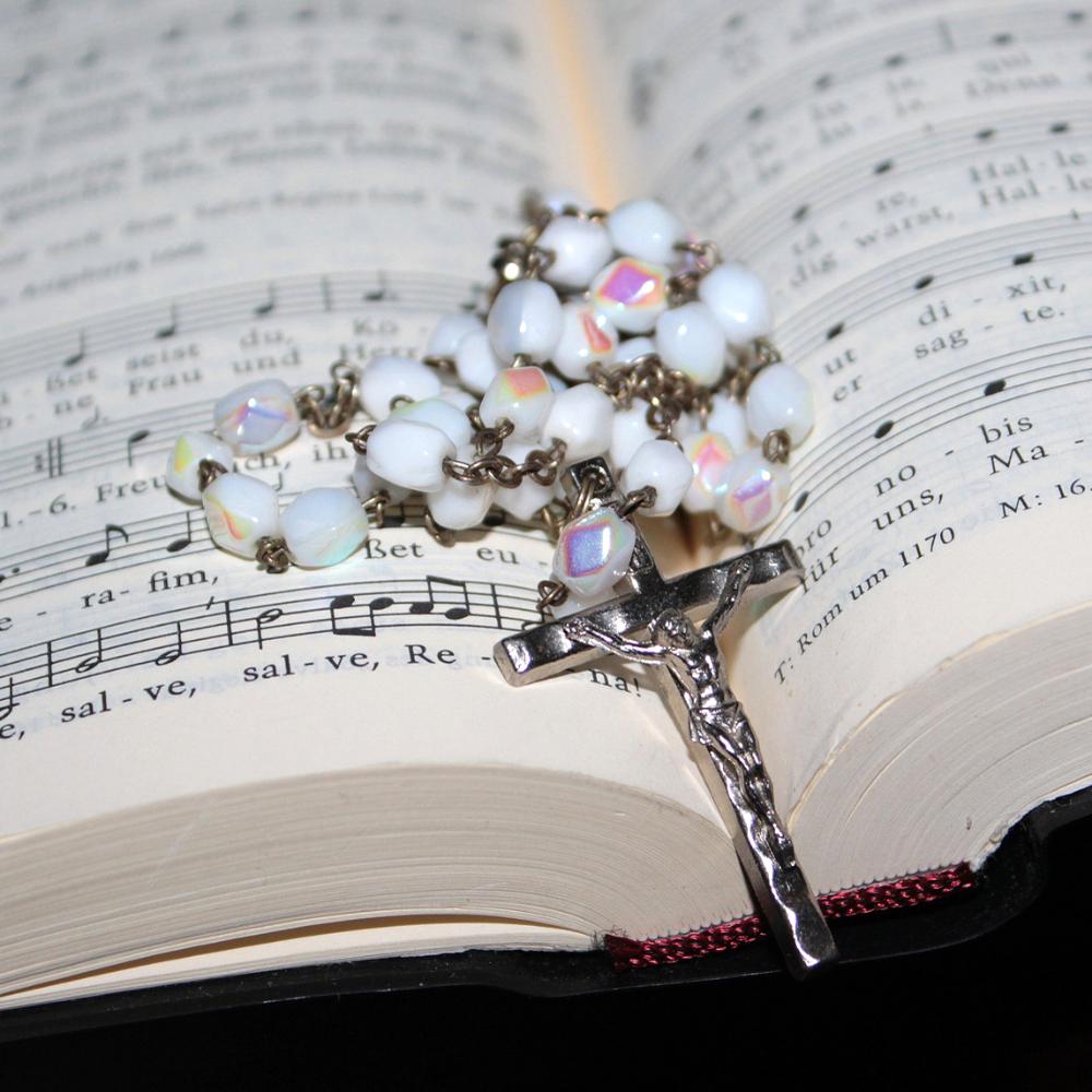 Öppen sångbok med pärlor och kors ovanpå.