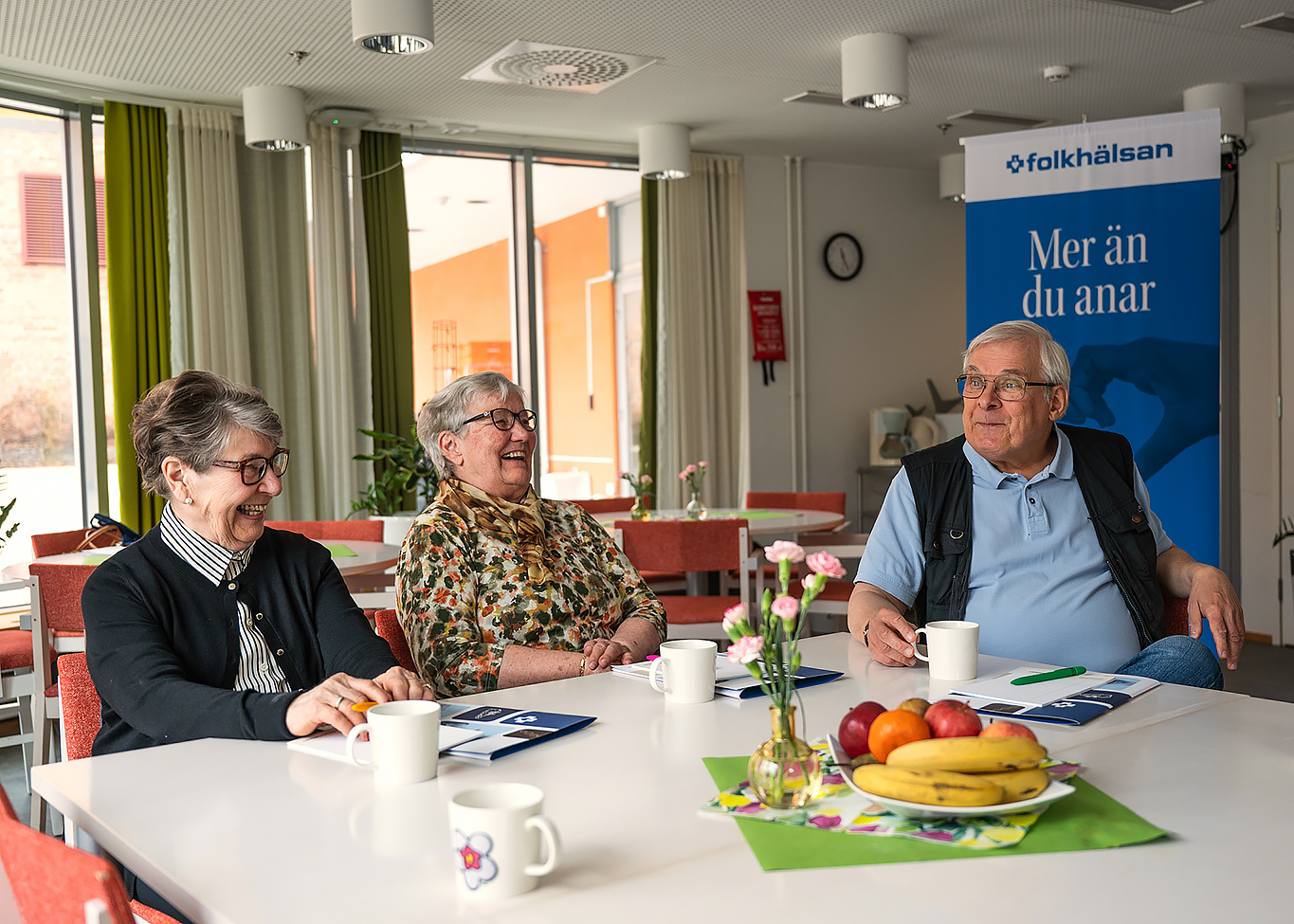 Tre pesoner samtalar kring kaffebordet.