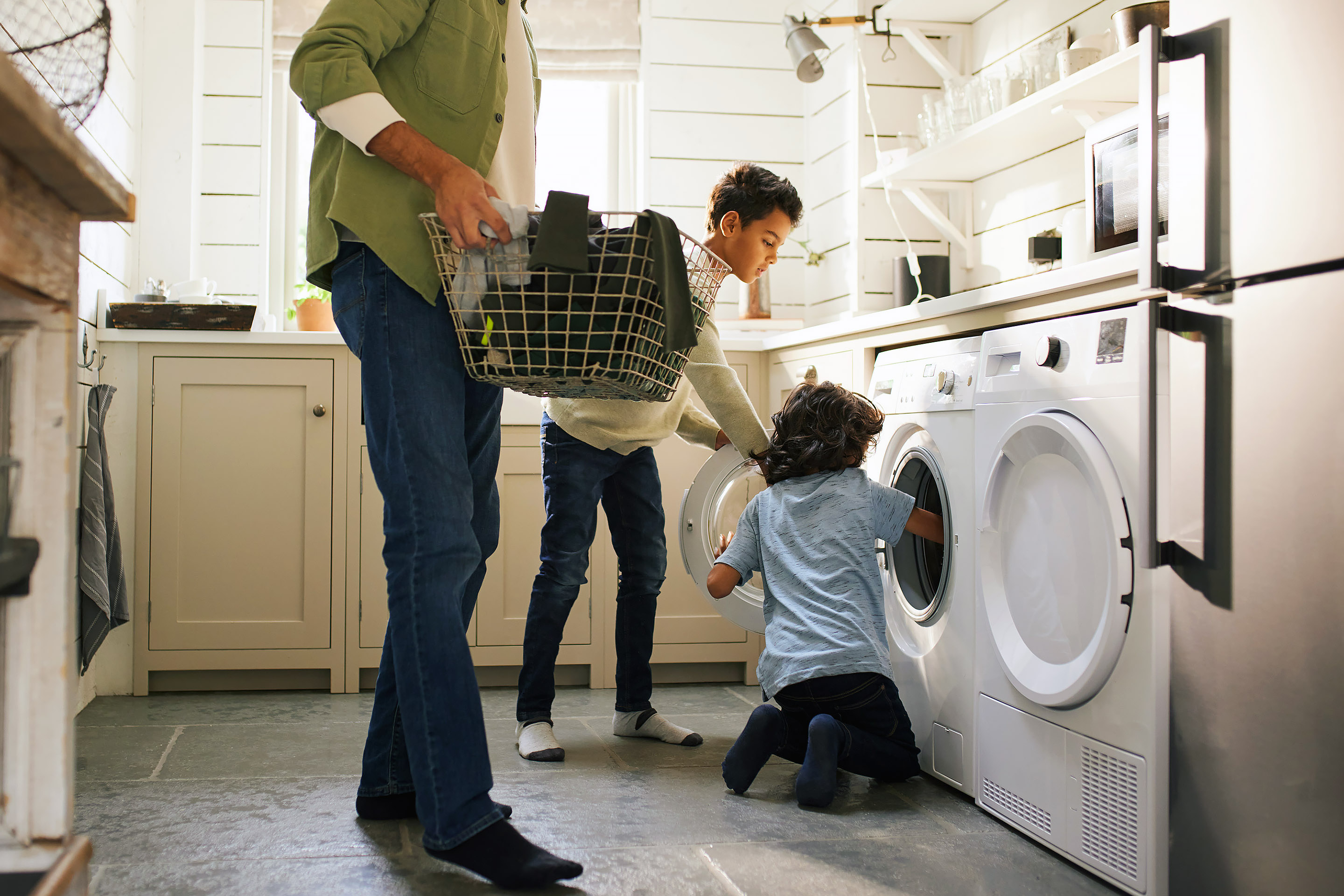 Två pojkar hjälper sin pappa med att tömma tvättmaskinen.
