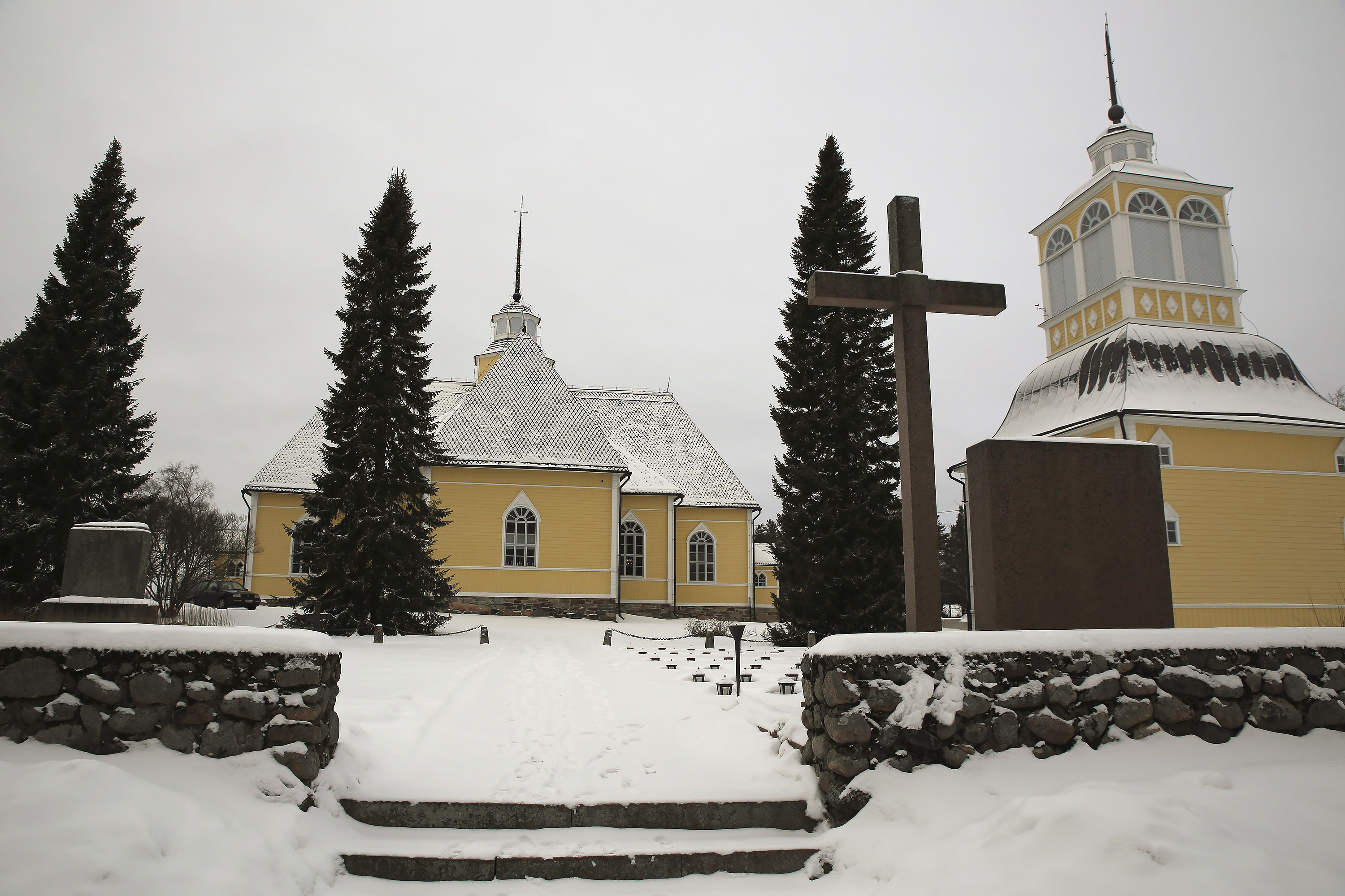 Lochteå kyrka och klockstapel lyser gula i det vita vinterlandskapet.