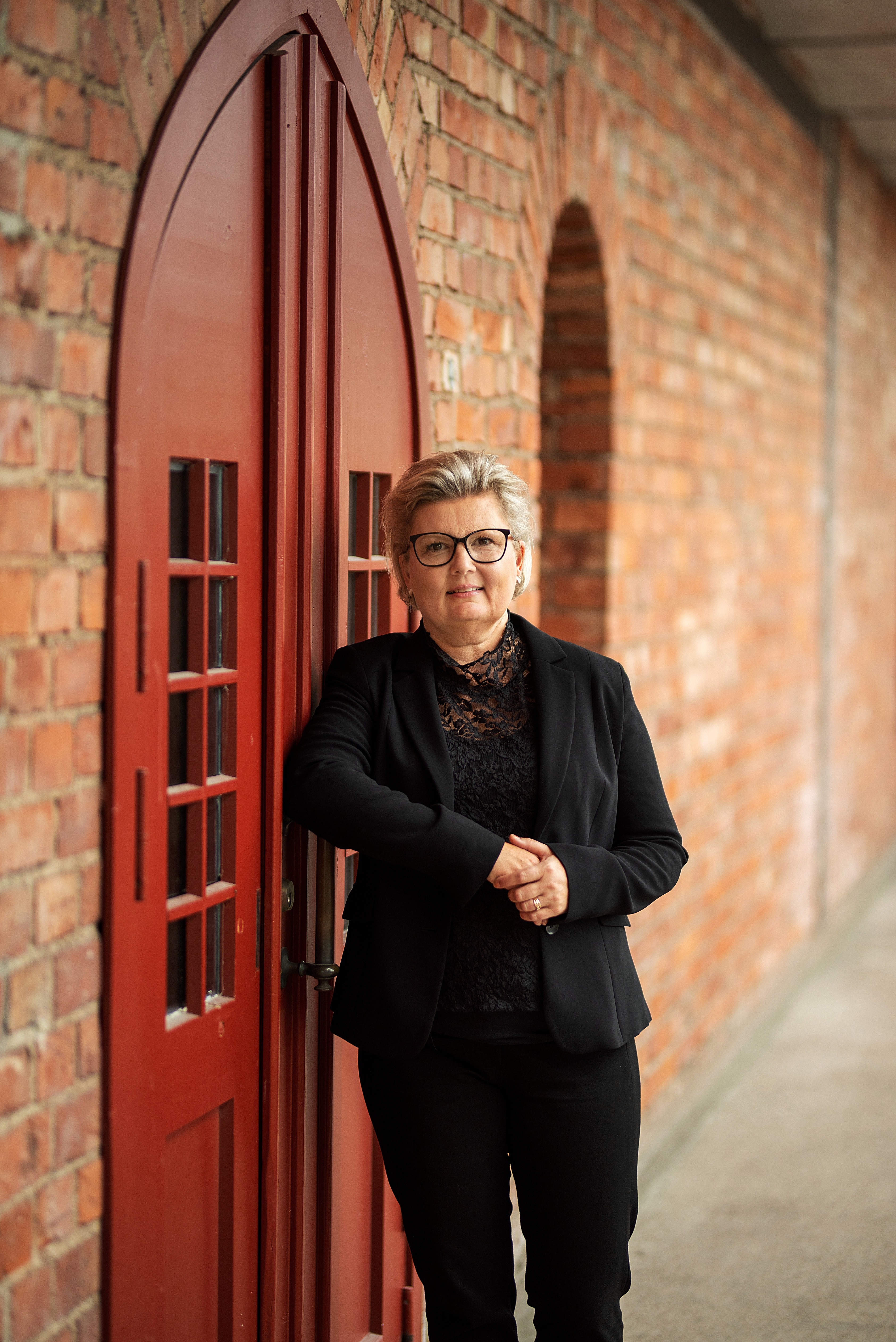 Maria Björkmark står lutad mot en dörr.